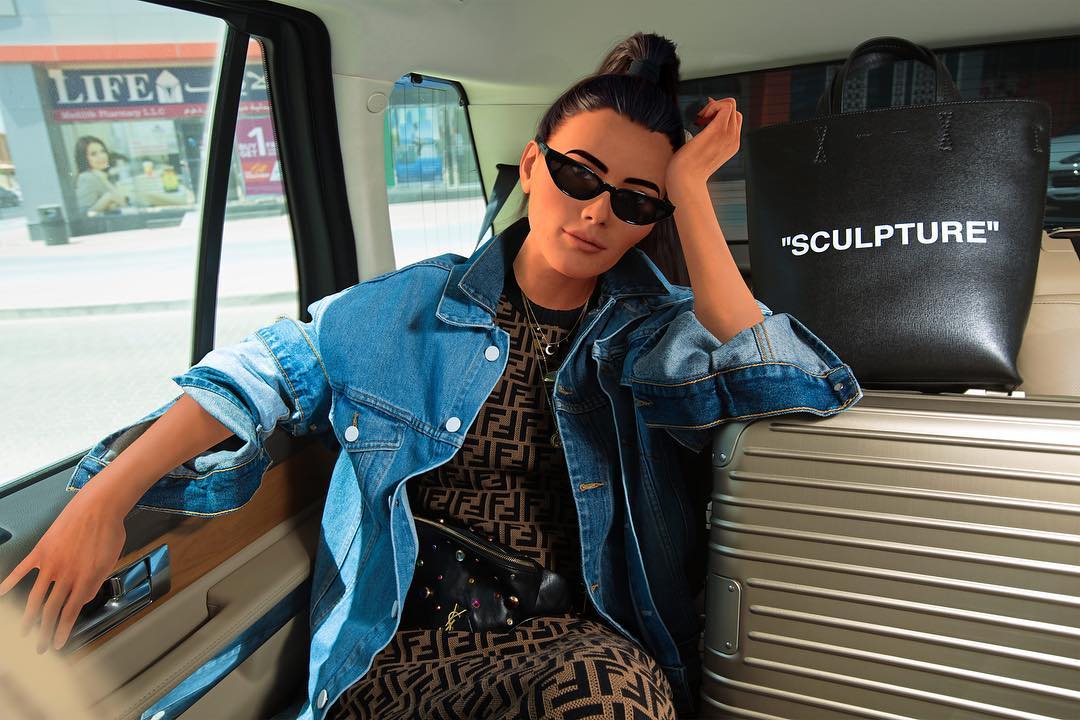 Virtual influencer Laila Blue with hair bun in denim jacket and designer print dress with black sunglasses in luxury car interior with Sculpture tote bag